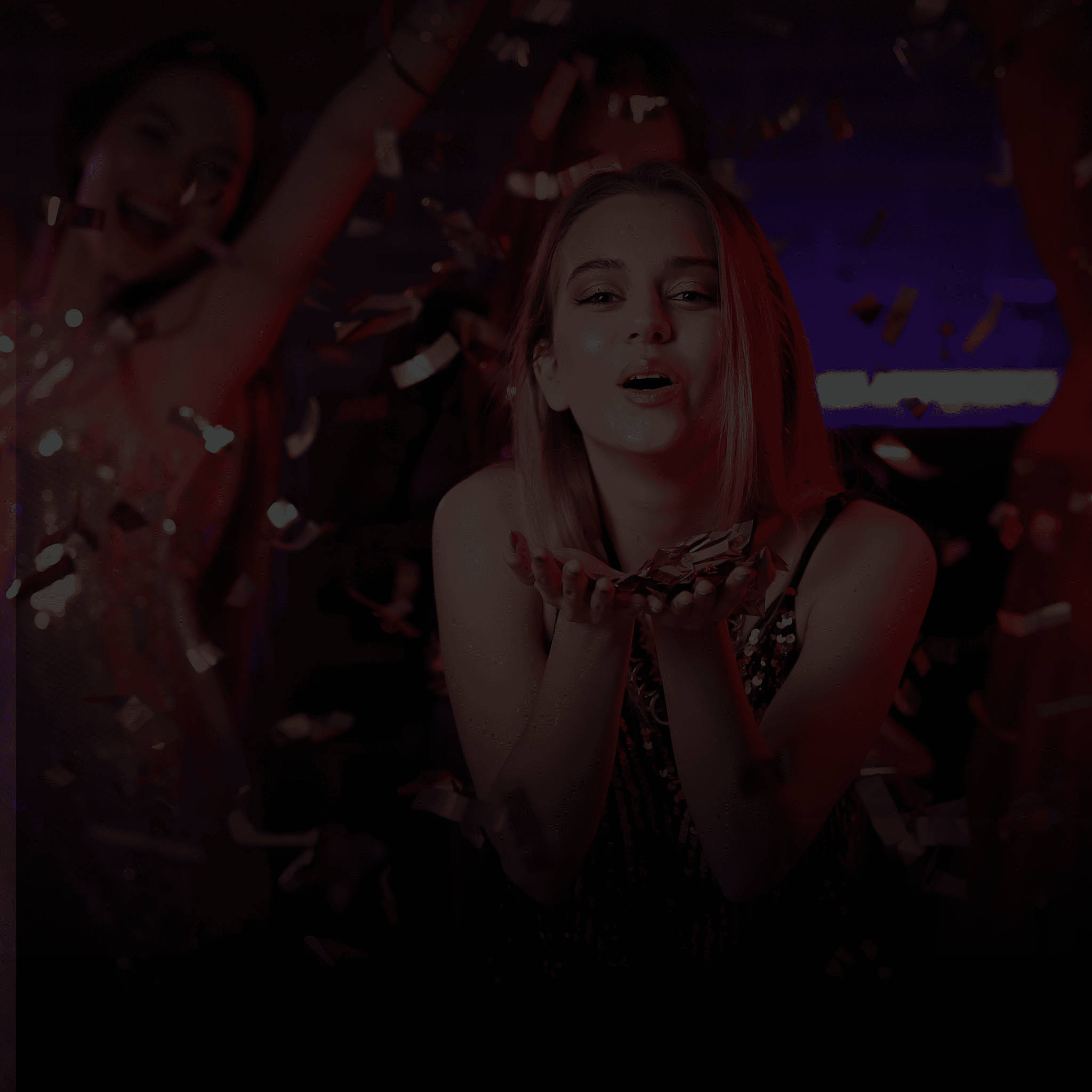 Woman with confetti falling around her against a dark background