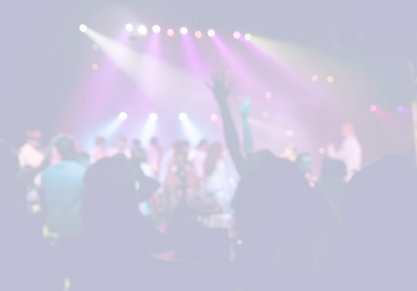 Blurred image of a concert with colorful lights and silhouettes of people.